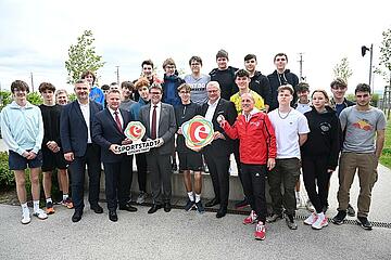 Bundesminister Martin Polaschek, Landesrat Heinrich Dorner und Bürgermeister Thomas Steiner gemeinsam mit HTL-Direktor Thomas Schober und Rolf Meixner sowie HTL-Schülern, die die Leichtathletik-Arena für ihr Training nutzen. 