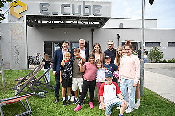 Bürgermeister Thomas Steiner gemeinsam mit Bundesministerin Claudia Plakolm, Nationalrat Christoph Zarits (l.) und dem 1. Vizebürgermeister Istvan Deli sowie Kindern vom Ferienspiel im E_Cube. 