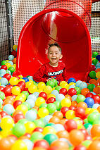 Innenansicht Indoorspielplatz Kind rutscht ins Bällebad