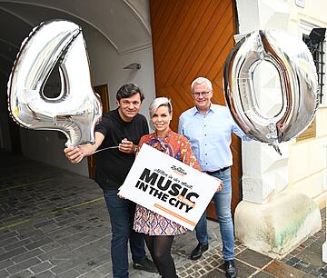Bürgermeister Thomas Steiner, Sängerin Tina Well und Musiker Wolfgang Glöckl freuen sich über das 40. Konzert bei Music in the City.