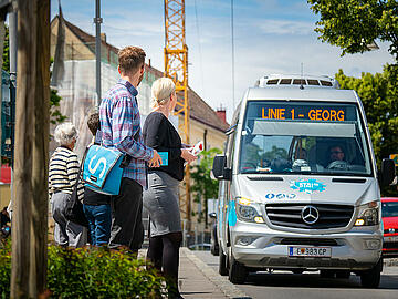 2 Personen warten an der Haltestelle auf den Eisenstädter Stadtbus